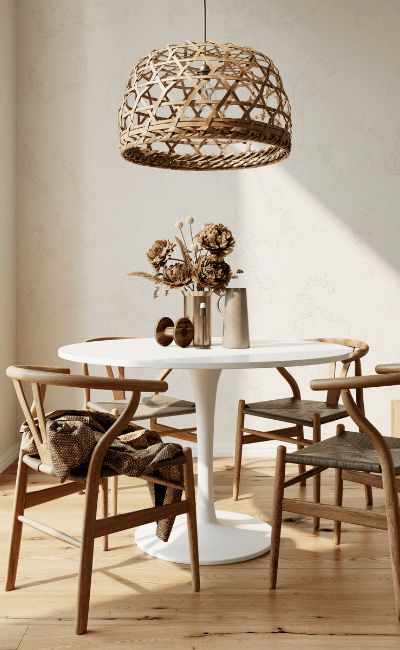 Breakfast nook with a round white table, wishbone chairs and a woven rattan pendant