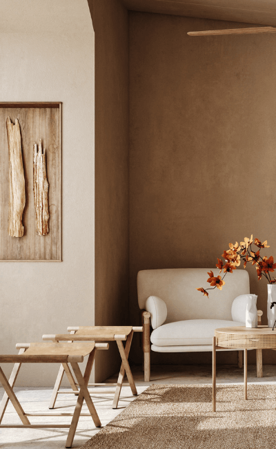 Sitting room with a warm clay-colored wall, cream armchair and wood side tables