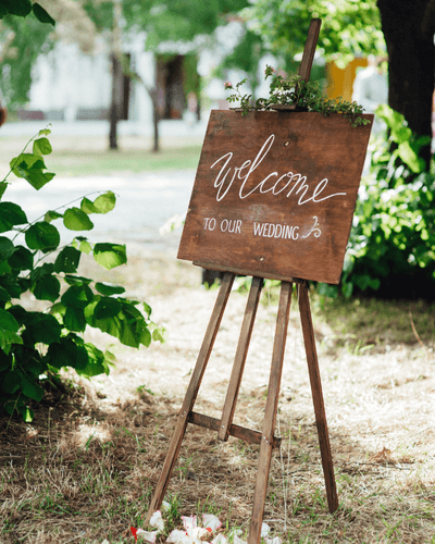 Wooden welcome sign on an easel at an outdoor wedding
