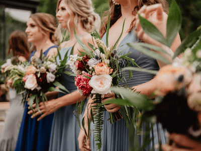 Bridesmaids holding bouquets of roses and greenery
