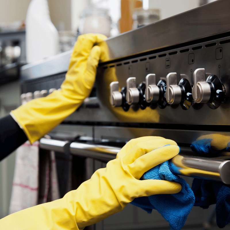 Cleaner wiping down kitchen appliances in an empty home