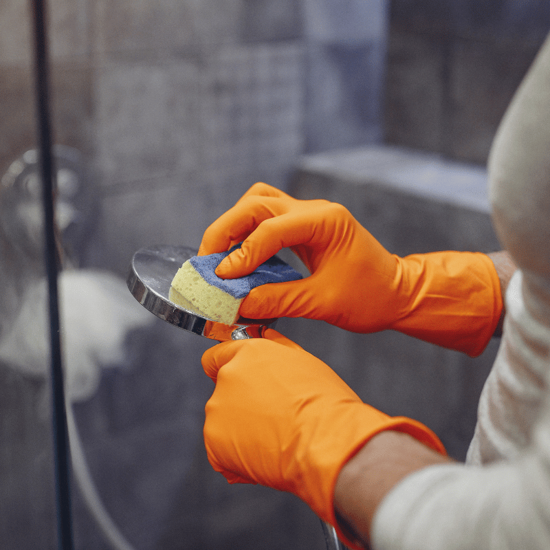 Cleaner scrubbing a tiled shower during a deep clean