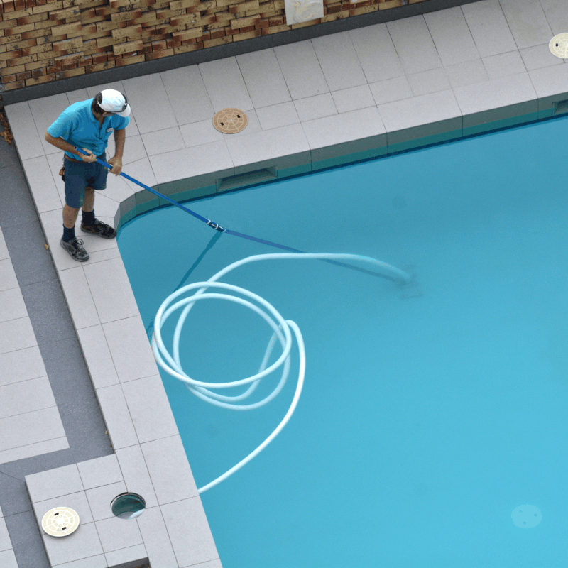 Aerial view of a technician cleaning a backyard pool