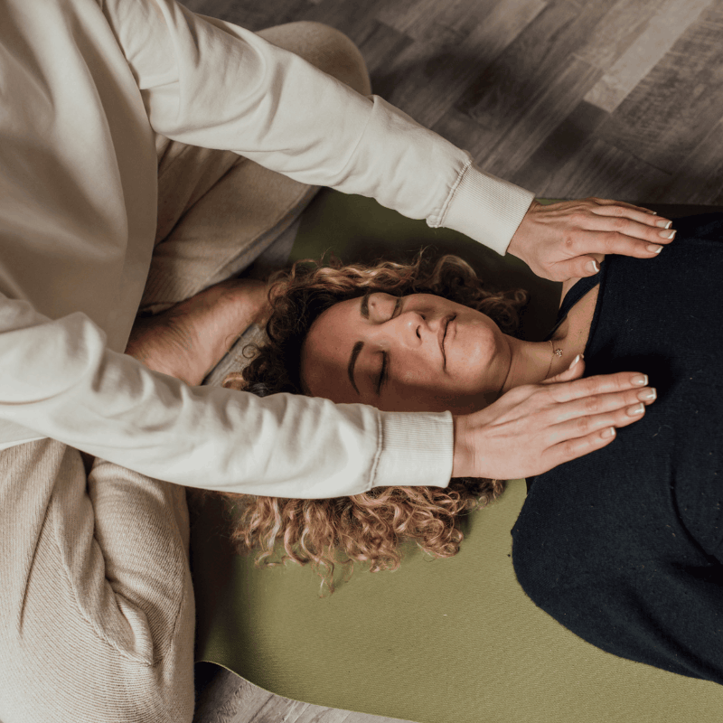Reiki practitioner resting her hands over a client on a treatment table