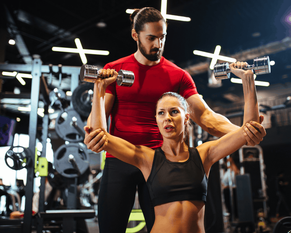 Personal trainer supporting a client in the gym